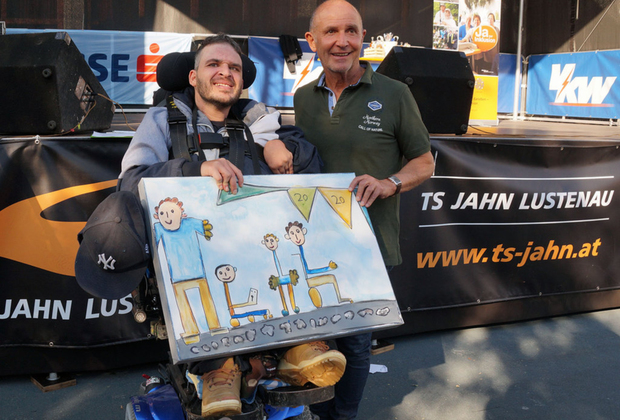 Ein Mann im Rollstuhl gibt einem anderen Mann ein Bild. 